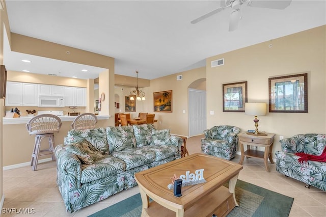 living room featuring light tile patterned flooring and ceiling fan with notable chandelier