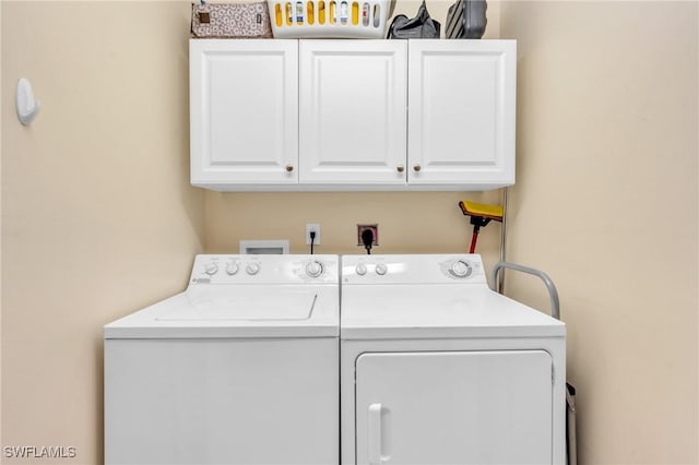 clothes washing area with cabinets and washing machine and clothes dryer