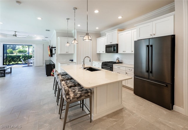 kitchen with ceiling fan, sink, black appliances, a center island with sink, and white cabinets