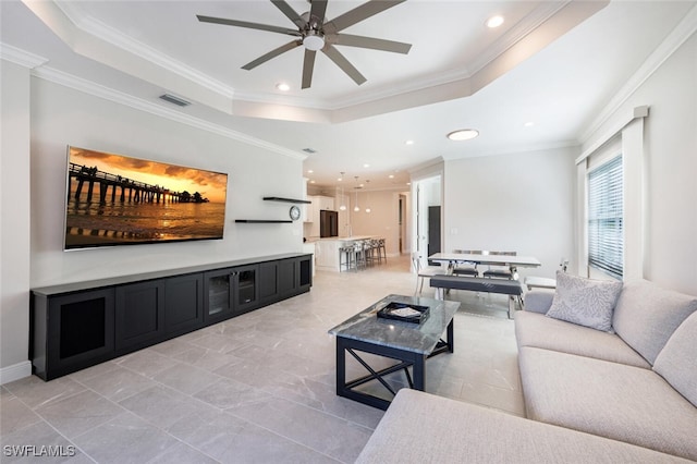 living room featuring a raised ceiling, ceiling fan, and ornamental molding