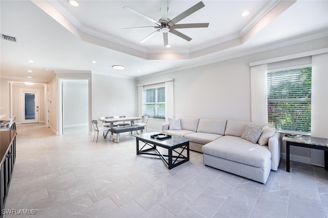 living room with a tray ceiling, ceiling fan, and crown molding