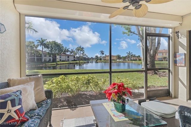 sunroom featuring ceiling fan and a water view