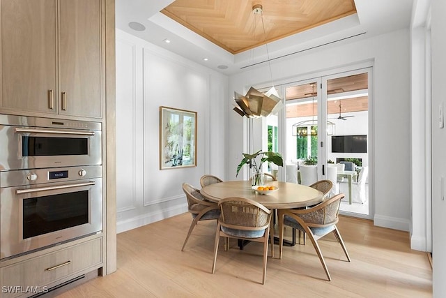 dining room featuring light wood-type flooring, a raised ceiling, and wood ceiling