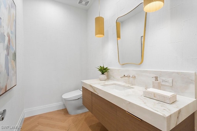 bathroom with vanity, parquet floors, and toilet