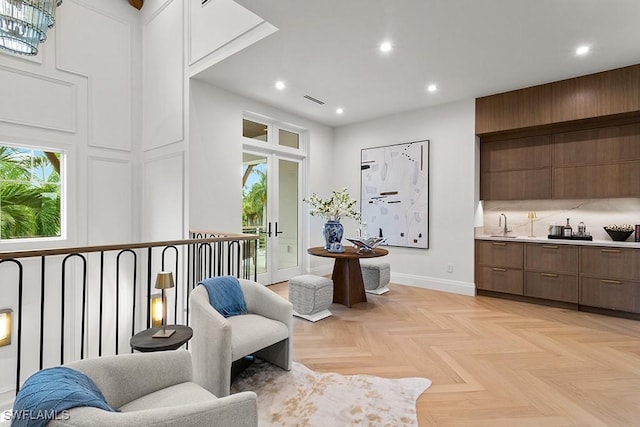 living area with sink, light parquet floors, and a high ceiling