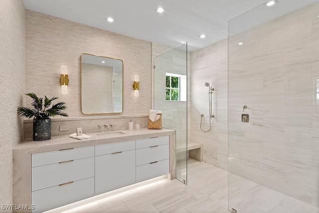 bathroom featuring a tile shower, vanity, and tile walls