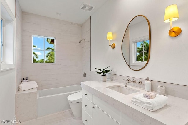 full bathroom with vanity, tiled shower / bath combo, and toilet