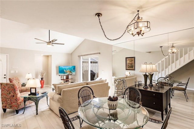 dining room featuring light wood-type flooring, ceiling fan with notable chandelier, and lofted ceiling