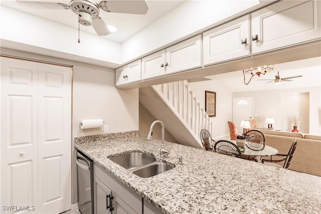 kitchen featuring light stone counters, sink, ceiling fan, and stainless steel dishwasher