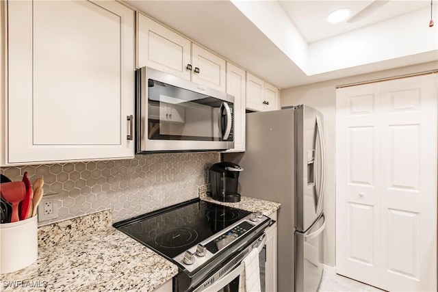 kitchen with tasteful backsplash, light stone countertops, white cabinets, and stainless steel appliances