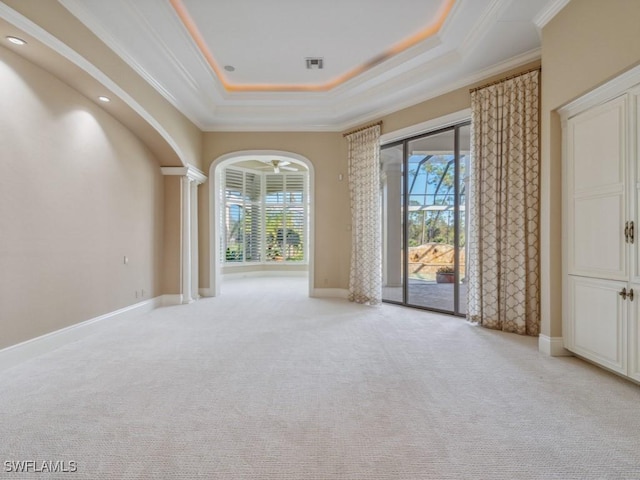 unfurnished room featuring a tray ceiling, arched walkways, baseboards, and ornamental molding