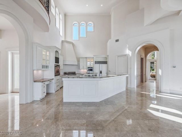 kitchen featuring premium range hood, arched walkways, and marble finish floor