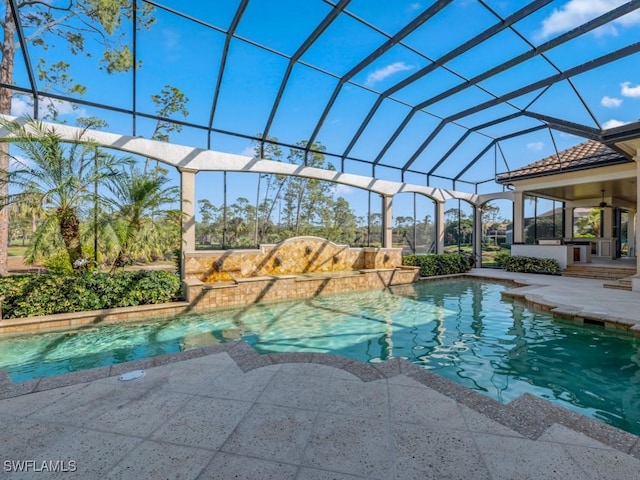 pool with a patio area, glass enclosure, and a ceiling fan