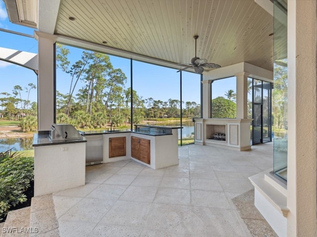 view of patio / terrace with area for grilling, a ceiling fan, a water view, and exterior fireplace