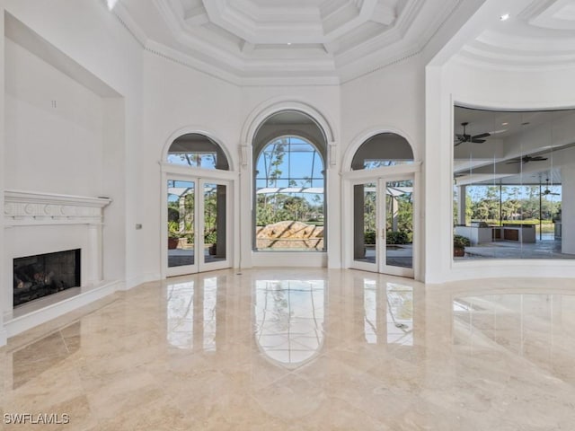 interior space featuring crown molding, a high ceiling, a fireplace with raised hearth, and french doors