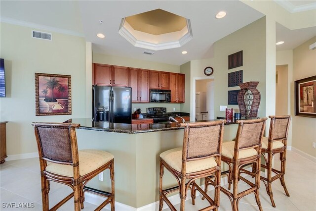 kitchen featuring a breakfast bar area, dark stone countertops, crown molding, and black appliances