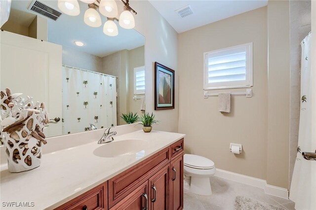 bathroom with tile patterned flooring, vanity, a chandelier, and toilet