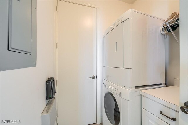 clothes washing area with stacked washing maching and dryer and electric panel