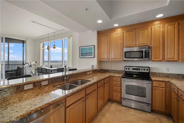 kitchen featuring light stone countertops, stainless steel appliances, sink, a water view, and hanging light fixtures