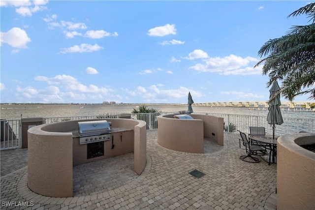 view of patio / terrace featuring a water view, exterior kitchen, and grilling area