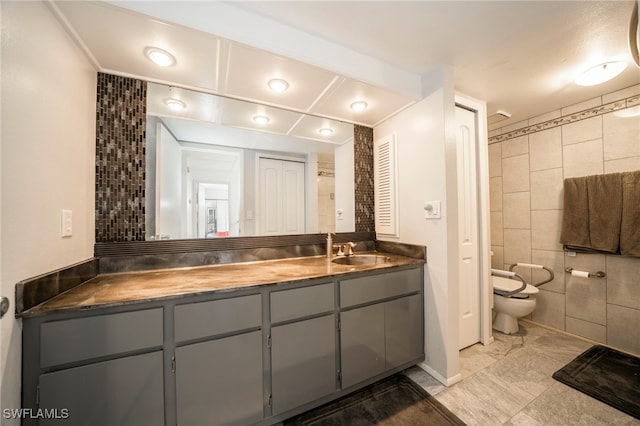 bathroom featuring vanity, tile walls, and toilet