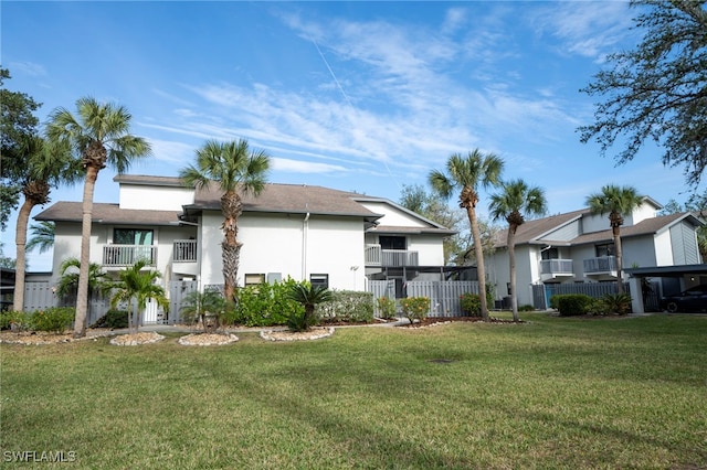 rear view of house featuring a balcony and a yard