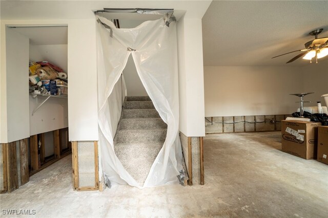 staircase with concrete floors and ceiling fan