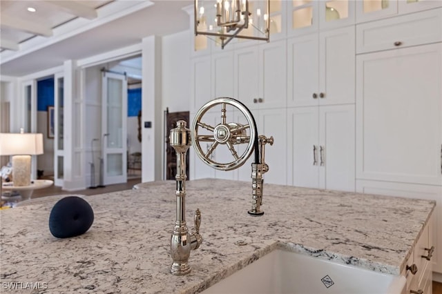 details with pendant lighting, light stone countertops, sink, and white cabinets