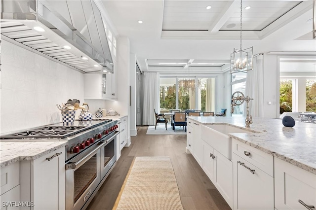 kitchen with white cabinetry, double oven range, a healthy amount of sunlight, and exhaust hood