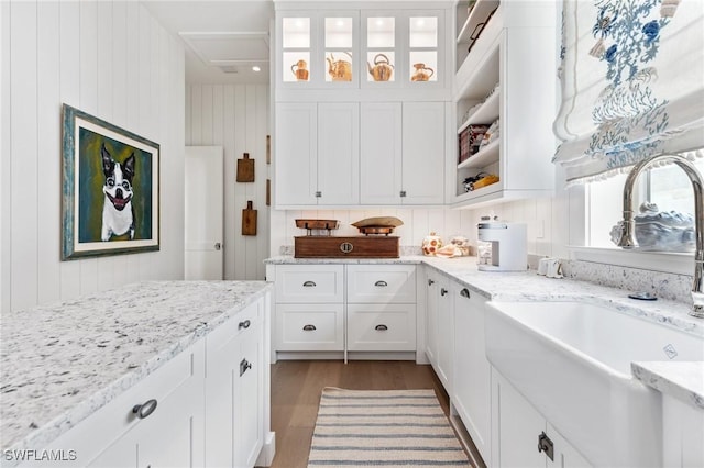 kitchen with light stone countertops, sink, dark wood-type flooring, and white cabinets