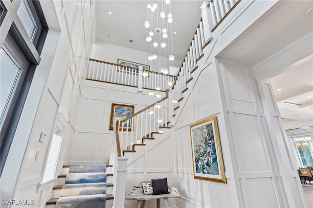 stairway with a high ceiling and a notable chandelier