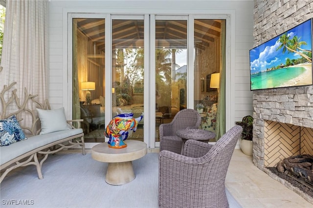 sunroom featuring plenty of natural light and an outdoor stone fireplace