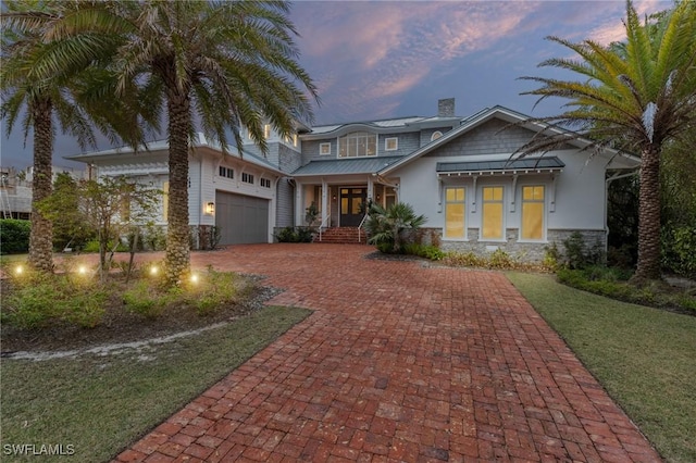 view of front facade featuring a garage, a yard, and covered porch