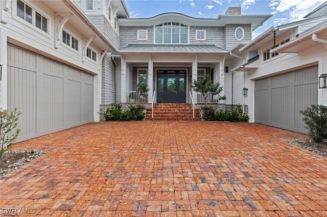 doorway to property featuring french doors, a garage, and covered porch