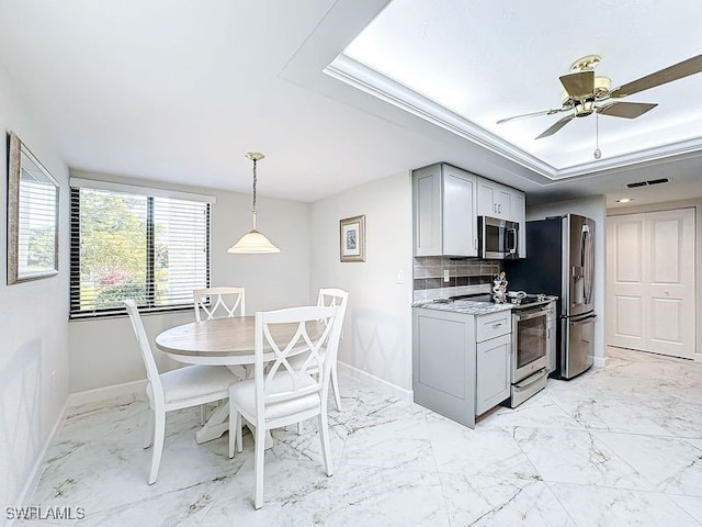 kitchen featuring ceiling fan, gray cabinets, light stone countertops, appliances with stainless steel finishes, and tasteful backsplash