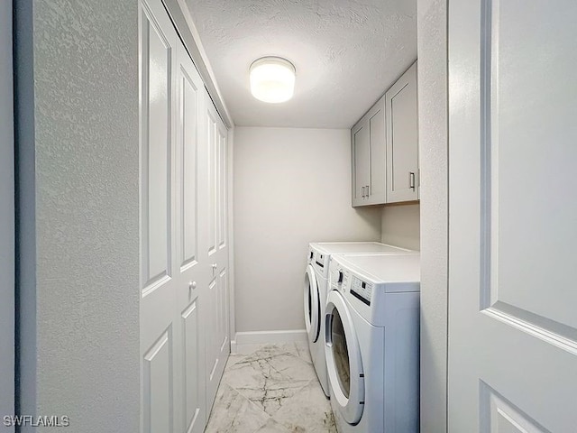 clothes washing area featuring cabinets, a textured ceiling, and washing machine and clothes dryer