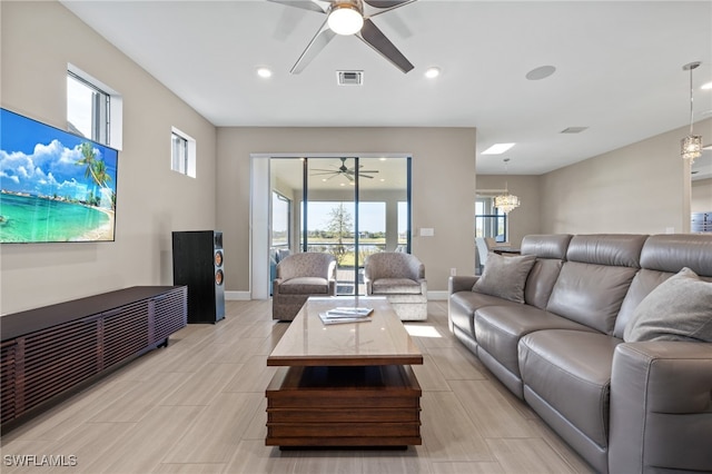 living area featuring baseboards, visible vents, and ceiling fan with notable chandelier