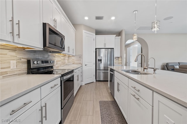 kitchen with white cabinetry, sink, stainless steel appliances, tasteful backsplash, and decorative light fixtures