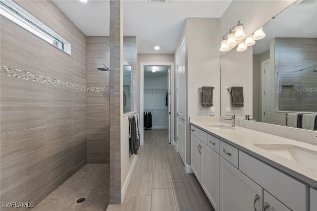 full bathroom with a sink, double vanity, walk in shower, and a walk in closet