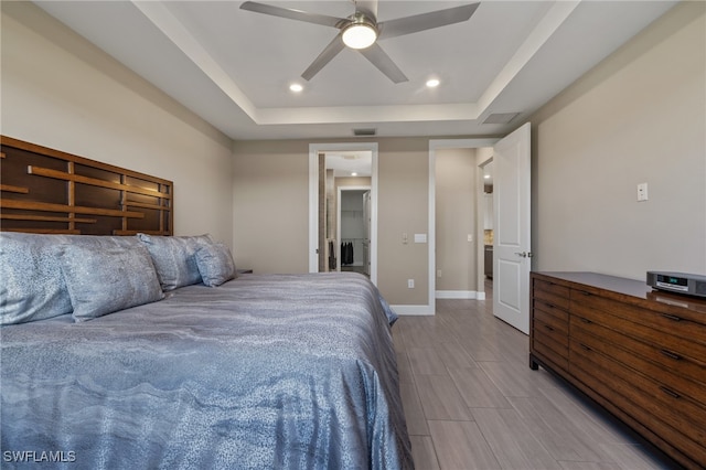 bedroom featuring ensuite bathroom, a raised ceiling, and ceiling fan