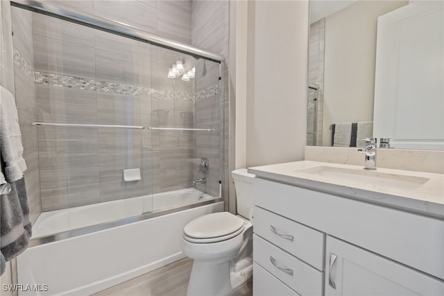 bathroom with enclosed tub / shower combo, vanity, wood finished floors, and toilet