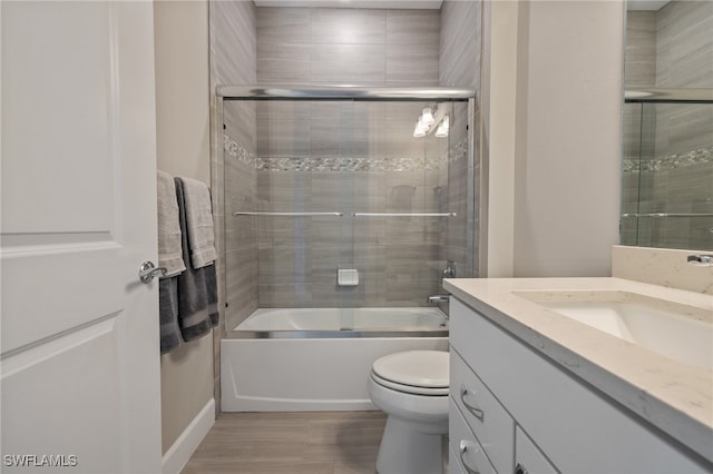 bathroom with toilet, shower / bath combination with glass door, wood finished floors, and vanity