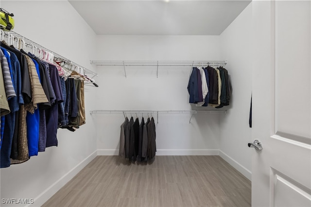 walk in closet with light hardwood / wood-style flooring