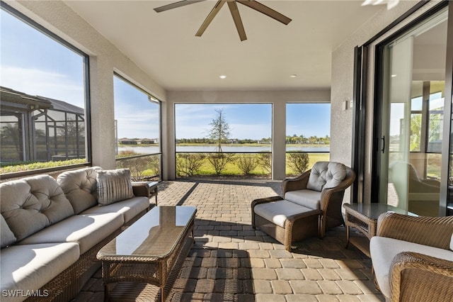 sunroom featuring a ceiling fan and a water view