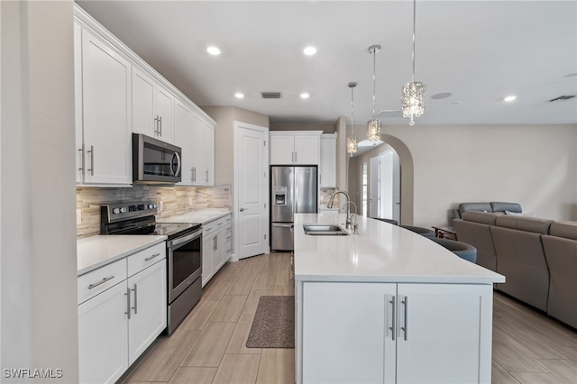 kitchen with arched walkways, visible vents, open floor plan, appliances with stainless steel finishes, and backsplash