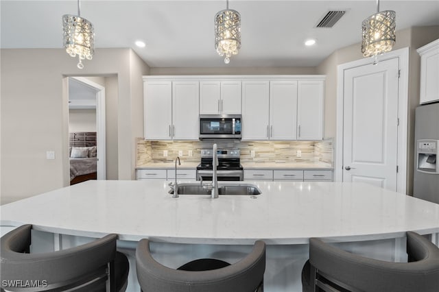 kitchen featuring decorative light fixtures, white cabinetry, and stainless steel appliances