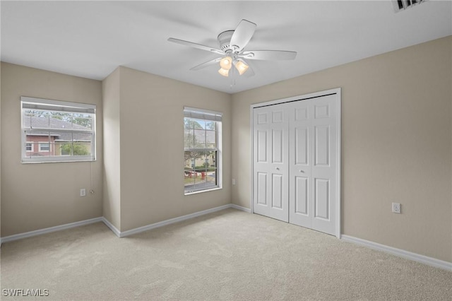 unfurnished bedroom featuring visible vents, light carpet, a ceiling fan, a closet, and baseboards