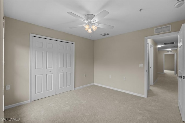 unfurnished bedroom featuring light colored carpet, a closet, and ceiling fan