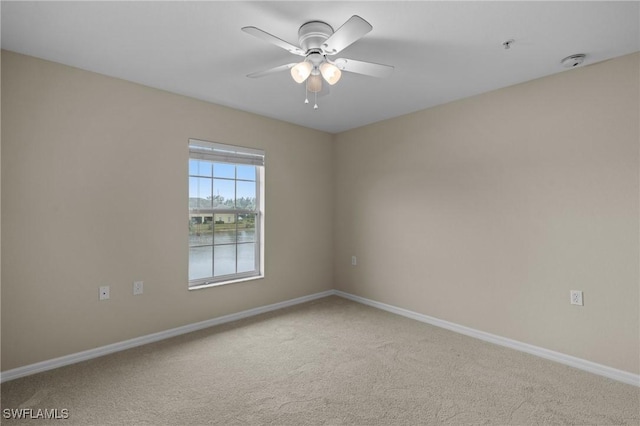 unfurnished room with carpet flooring, a ceiling fan, and baseboards