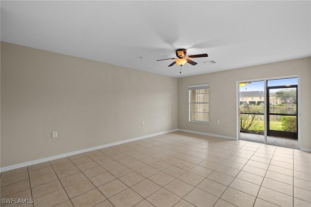 spare room featuring light tile patterned floors, a ceiling fan, visible vents, and baseboards